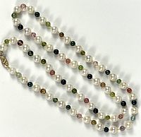 Full view of the necklace featuring alternating pearls and colored glass beads, arranged in a loose coil to show length and bead pattern.