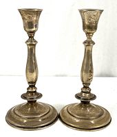 Front view of the pair of 10-inch tall sterling silver candlesticks with visible tarnish and patina.
