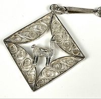 Close-up of the sterling silver llama pendant with filigree swirl work and raised llama figure in the center.