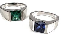 Two sterling silver rings side by side, one with dark green glass accent, the other with dark blue glass accent