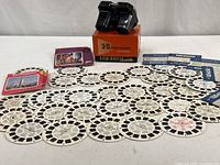 View-Master viewer with original orange box and multiple reels arranged on flat surface