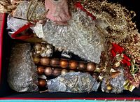 Open red box showing assorted gold ornaments, garland, stems and bubble wrap