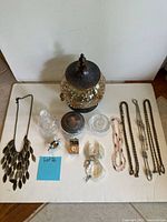 Full lot view showing necklaces, glass jars, pendant watch, dolphin figurine