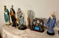 Full group of statues, mantel clock and crucifix on table
