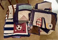 Stacked quilts and pillowcases displaying various patchwork motifs