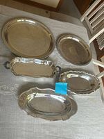 Five silver-plated trays on table, full view