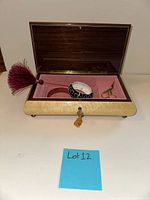 Open music box showing interior lining, bracelets, scissors, tassel