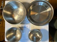 Top view of four stainless items: three bowls and pie plate
