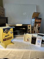 All three appliances grouped: GE toaster oven, boxed Black & Decker carving knife, yellow electric can opener