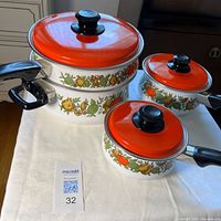 Three enamel pots with red lids displaying Spice of Life pattern