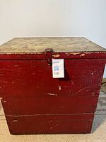 Front view of red wooden chest showing latch and worn paint