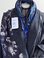 Full view of coat on mannequin with black floral scarf and paisley scarf at neckline