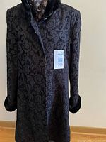 Front view of black jacquard coat on hanger showing pattern and faux fur collar/cuffs