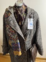 Front view of coat on mannequin with one scarf, purse and gloves visible