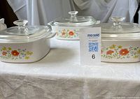 Front view of three Corning Ware Wildflower casseroles with lids