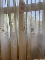 Full view of sheer beige curtains with floral embroidery