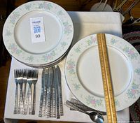 Stack of Prestige pattern plates with flatware sets displayed