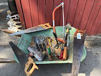 Overall lot showing wheelbarrow filled with saws and garden tools