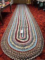 Full view of the multicolour braided runner rug on carpeted floor