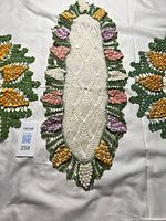 Oblong crocheted doily with multicolour grape cluster border
