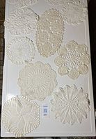 Top-down view of all ten crochet doilies arranged on surface