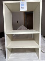 Front view of white three-shelf melamine unit showing overall structure