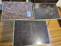 Three tray tops showing parquet, floral butterfly, and mottled designs on folding frames