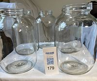 Front view of five clear glass gallon jars on table