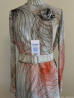 Back view of silver swirl gown on hanger with belt and brooch