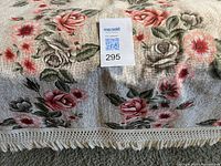 Close-up of beige/cream bedcover showing rose pattern and fringe