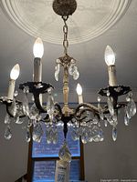 Full view of chandelier lit showing crystals and candle sleeves