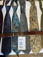 All seven ties and belt laid out showing patterns and colours
