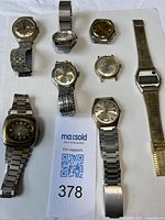 Front view of all seven watches showing dials and bracelets