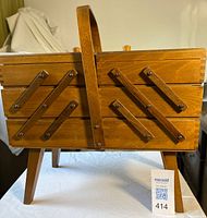 Closed wooden cantilever sewing box on legs with handle, frontal view