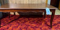Front view of solid wood coffee table showing scalloped apron and legs