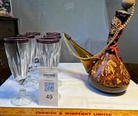 Flask positioned beside six fluted glasses showing overall lot