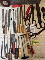 Overview of laid-out tools: rasps, chisels, knives, shears, wrench, punches, measuring tape disc visible