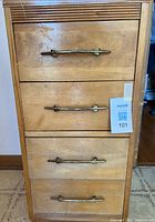Front view of wooden cabinet showing four drawers and metal handles