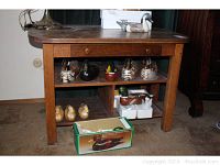 Front view of a golden oak rectangular library table showing the single drawer open and a lower shelf with sections containing wooden duck figurines (not included).