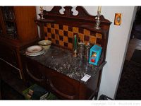 Full view of vintage washstand showing marble top, tile backsplash, candle holders, and various silverware and dishes on top