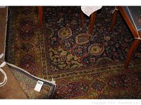 Close up corner view of the rug showing the intricate border patterns and the tag with lot number.