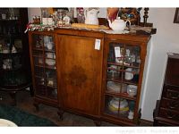 Front view of the English china cabinet showing the glass paneled doors on both sides and a solid wood central door. Cabinet contains various plates and glassware.
