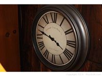 Close-up of the round wall clock with Roman numerals and 'Grosvenor Clock Works Co. London England' on the face.