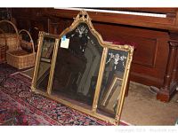 Full view of three-panel mirror with etched glass and gold frame leaning against piano