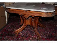 Front angle view of table showing marble top and wooden base