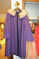 Purple vintage coat with fur collar hanging on wall hook