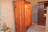 Side and front view of antique cedar wardrobe with door partially open showing its solid cedar construction and natural wood grain.