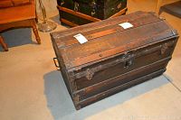 Larger wooden trunk viewed from above showing flat top with metal strips and wood wear.