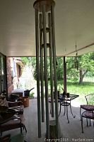 Large silver-tone aluminum wind chime with eight hollow tubes suspended from a circular wooden top