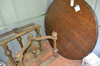 View of disassembled table parts including the round tabletop and wooden legs with turned design, showing condition and antique finish.